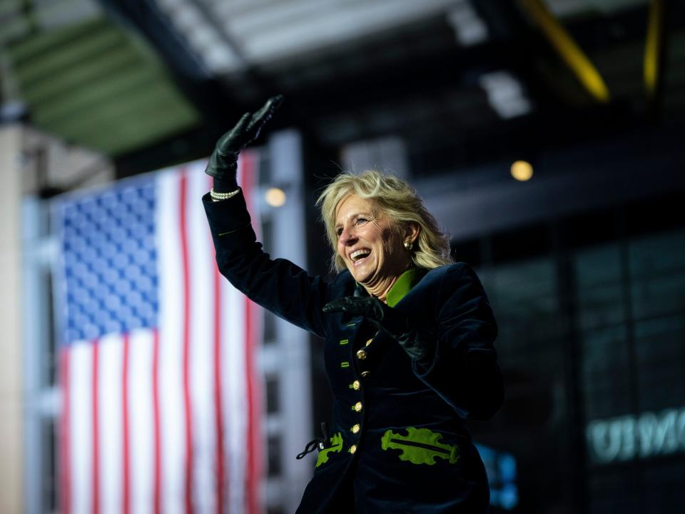 Dr. Jill Biden waves with an American flag in the background