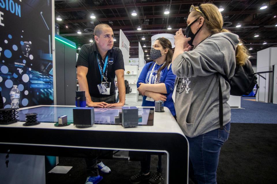 Juan Rodriguez, left, presents information on DyeMansion at the RAPID + TCT event at Huntington Place in Detroit on Wednesday, May 18, 2022. The event featured over 400 exhibitors sharing their latest ideas in 3D printing technology.