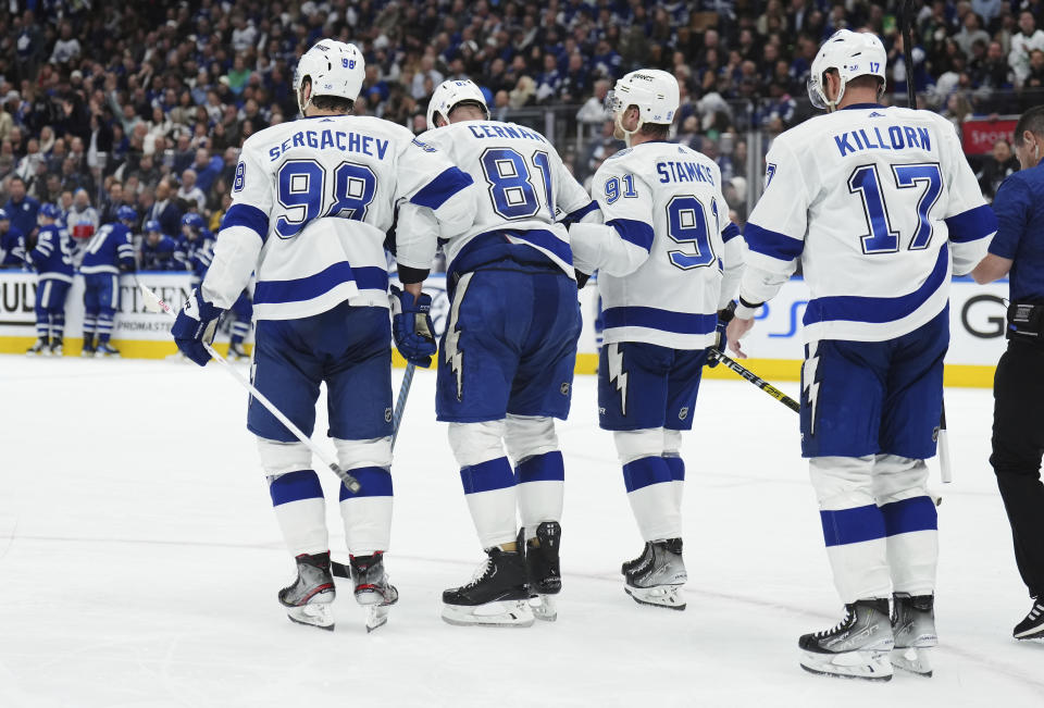 Tampa Bay Lightning defenseman Erik Cernak (81) is helped off the ice by Mikhail Sergachev (98) and Steven Stamkos (91) as Alex Killorn (17) watches during the second period of Game 1 of the team's first-round NHL hockey playoff series against the Toronto Blue Jays on Tuesday, April 18, 2023, in Toronto. (Nathan Denette/The Canadian Press via AP)