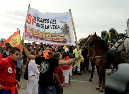 Revellers hold a banner in support of the Toro de la Vega next to Spanish Civil Guard officers before the start of the Toro de la Pena, formerly known as Toro de la Vega (Bull of the Plain) festival, in Tordesillas, Spain, September 13, 2016. REUTERS/Andrea Comas