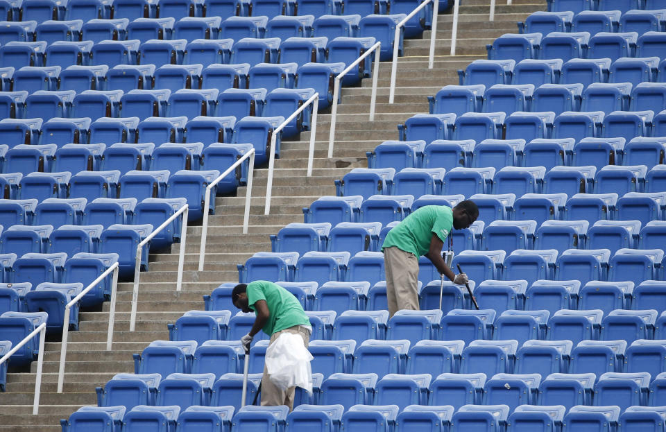 FILE - In this Sept. 10, 2015, file photo, workers clean the empty stands in Arthur Ashe Stadium after the women's semifinal matches were postponed because of rain at the U.S. Open tennis tournament in New York. (AP Photo/Kathy Willens, File)