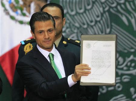 Mexico's President Enrique Pena Nieto shows the document after he signed into law a radical reform of the country's energy, at the National Palace in Mexico City December 20, 2013. REUTERS/Henry Romero