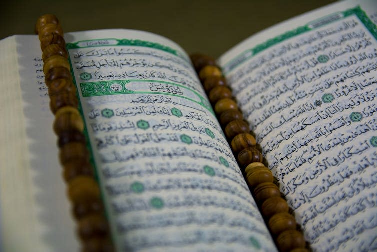 A close-up of an open Quran with a tasbeeh on it.