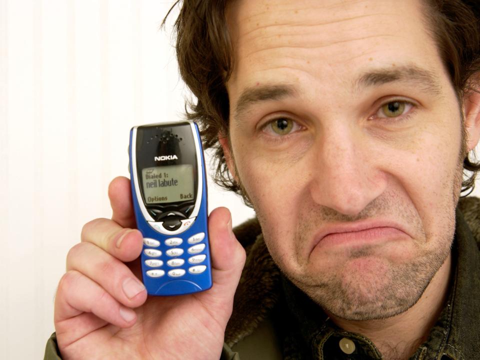 paul rudd pulls a face as he holds up a phone.