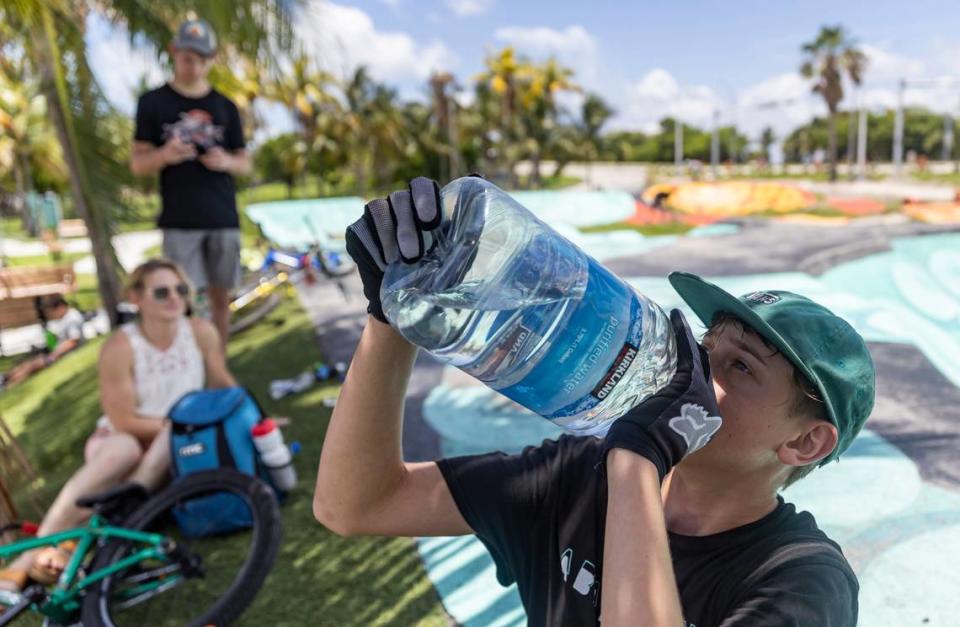 Aaron McElwain, de 13 años, bebe un poco de agua después de montar su moto scooter en Haulover Skateboard Park, el miércoles, 14 de junio de 2023, en Miami Beach, Florida.