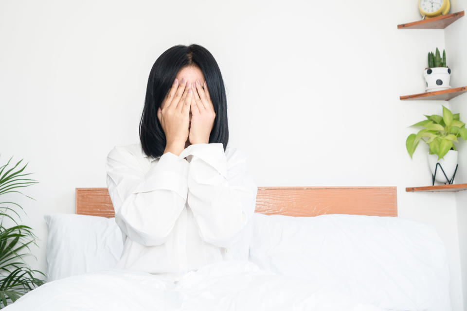A woman covering her face after waking up