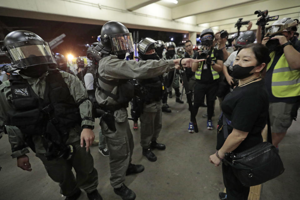 Police in riot gear ask a woman to take off her mask outside a train station in Hong Kong, Sunday, Nov. 3, 2019. Riot police stormed several malls in Hong Kong on Sunday in a move to thwart more pro-democracy protests, as the city's leader heads to Beijing for talks on deepening economic integration between the semi-autonomous Chinese territory and mainland China. (AP Photo/Dita Alangkara)