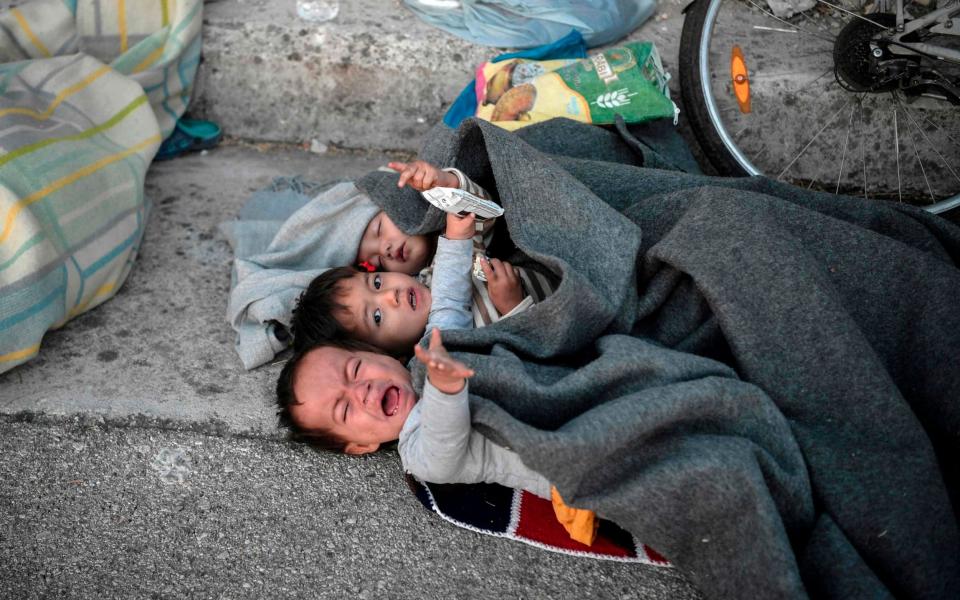 Children wake up after spending the night sleeping in a road - AFP