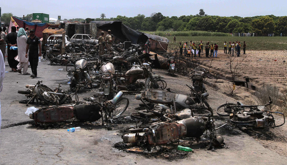 <p>Pakistan army soldiers stands guard while rescue workers examine the site of an oil tanker explosion at a highway near Bahawalpur, Pakistan, Sunday, June 25, 2017. An overturned oil tanker burst into flames in Pakistan on Sunday, killing more than one hundred people who had rushed to the scene of the highway accident to gather leaking fuel, an official said. (AP Photo/Iram Asim) </p>