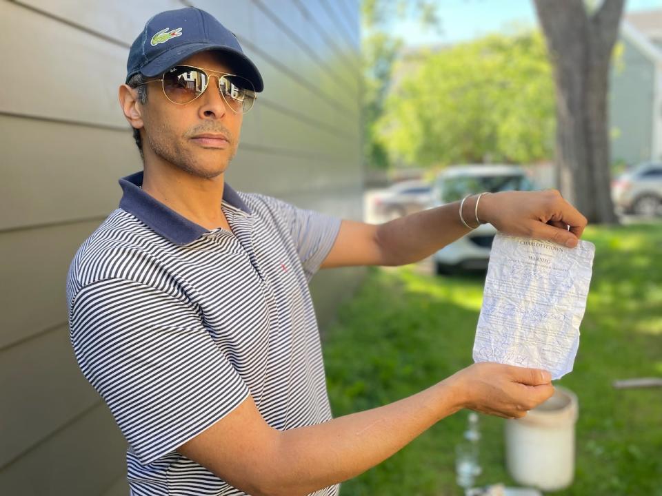 Mike Ross holds a notice from the city telling him he must cut his grass or face a fine. 