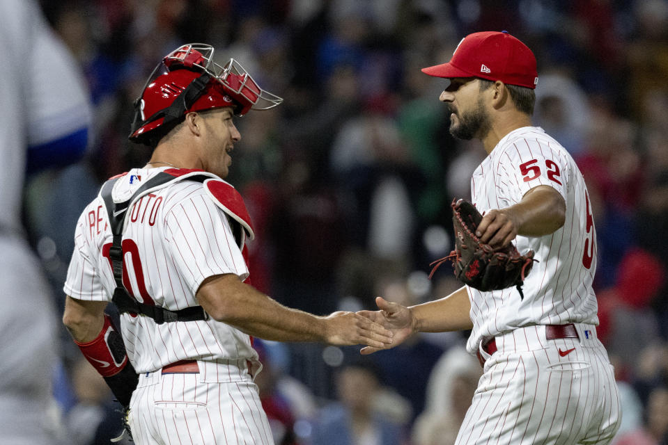 Philadelphia Phillies closing pitcher Brad Hand (52) and catcher J.T. Realmuto (10) celebrate after their team defeated the New York Mets in a baseball game, Monday, April 11, 2022, in Philadelphia. (AP Photo/Laurence Kesterson)