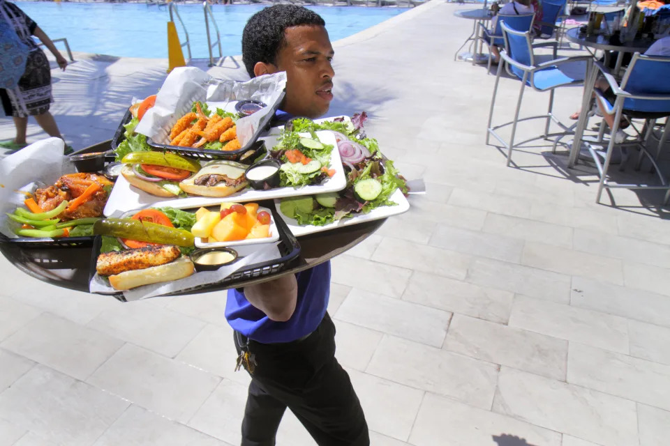 A waiter serving food from Tiki Bar & Grill at Crowne Plaza Hollywood Beach. (Photo by: Jeff Greenberg/Universal Images Group via Getty Images)