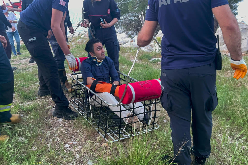 Rescue and emergency team members work with passengers of a cable car transportation system outside Antalya, southern Turkey, Friday, April 12, 2024. At least one person was killed and several injured Friday when a cable car pod in southern Turkey hit a pole and burst open, sending the passengers plummeting to the mountainside below, officials and local media said. Scores of other people were left stranded late into the night after the entire cable car system came to a standstill. (Dia Images via AP)