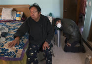 Ricardo Ledesma Carrasco, right, prepares a newly-refilled oxygen tank for his father Juan Jose Ledesma, 68, left, who is being treated for COVID-19 at home where he is isolating in Mexico City, Thursday, Dec. 31, 2020. (AP Photo/Marco Ugarte)