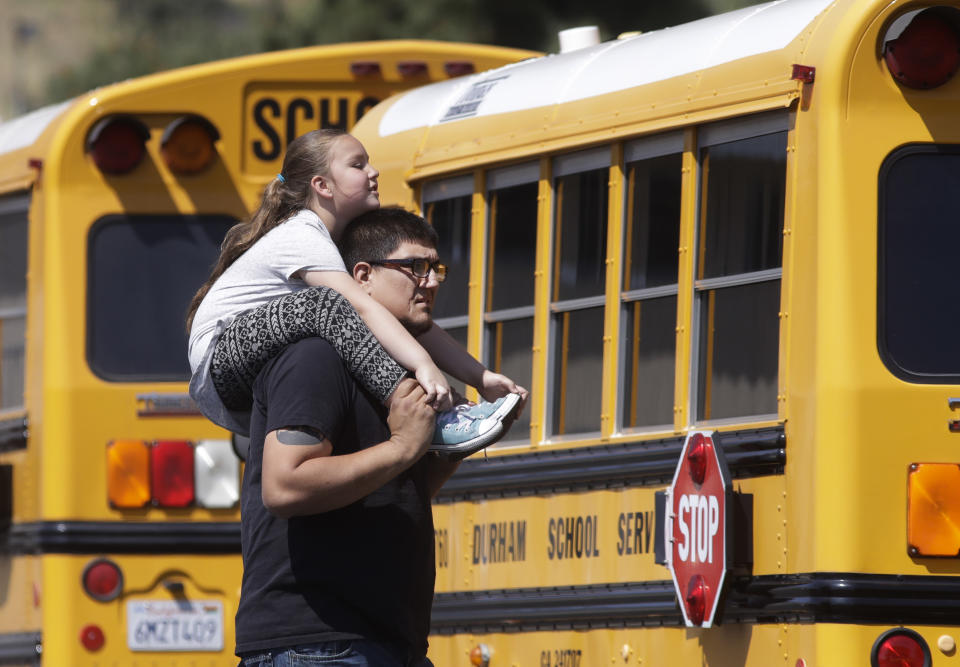 Nicholas Martinez carries his daughter, Monique, a kindergarten student at North Park Elementary School, on his shoulders after they were reunited at Cajon High School, Monday, April 10, 2017, in San Bernardino, Calif., after a deadly shooting occurred at the elementary school. (AP Photo/Jae C. Hong)