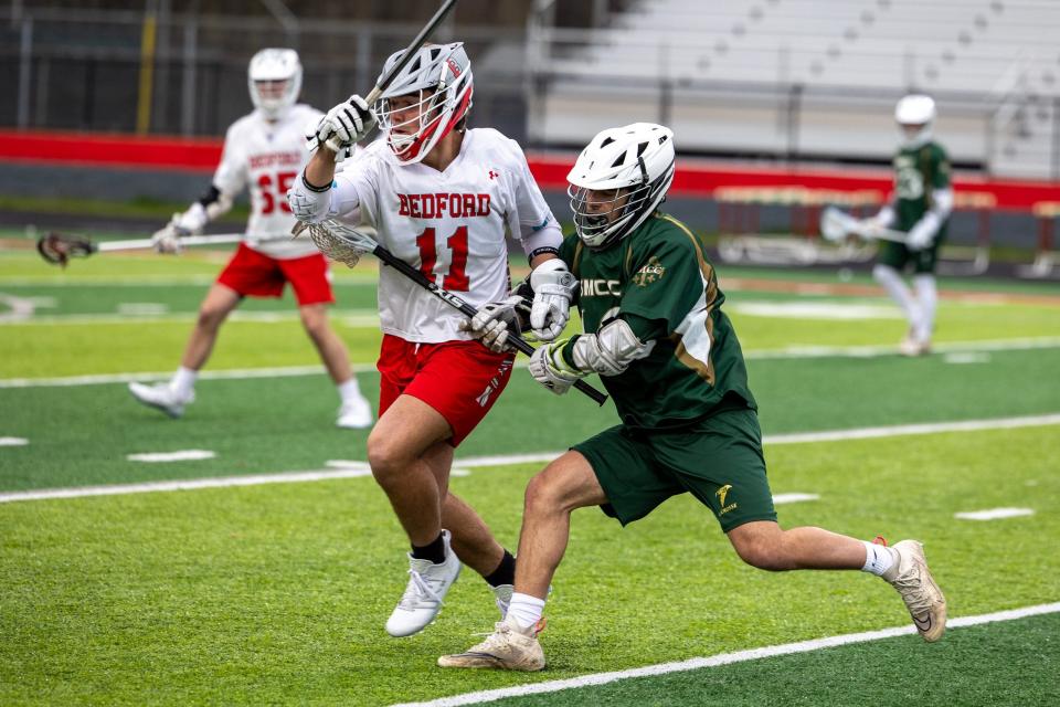 Dillon Kaun of Bedford (11) holds off St. Mary Catholic Central's Vito Galati in Friday night's lacrosse game. Bedford won 17-3.