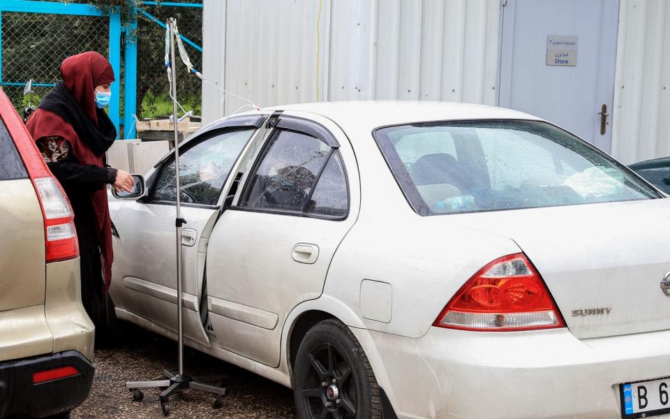 A Covid-19 patient take his treatment inside his car at the Saint Georges Hospital of Hezbollah in Beirut - NABIL MOUNZER/EPA-EFE/Shutterstock