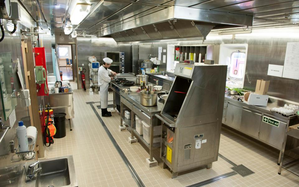 A chef cooking in a galley kitchen on board a merchant ship