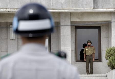 A North (R) and a South Korean army soldier stand guard as members of the Group of Eminent Persons of the Comprehensive Nuclear-Test-Ban Treaty Organization visit the border village of Panmunjom that has separated the two Koreas since the Korean War, in Paju, South Korea, in this June 26, 2015 file photo. REUTERS/Ahn Young-joon/Pool