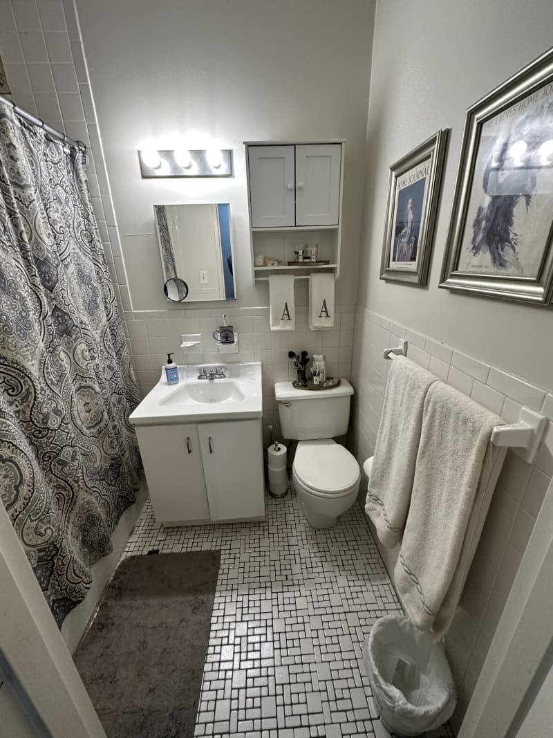 Two framed images in a white bathroom with tile floors.