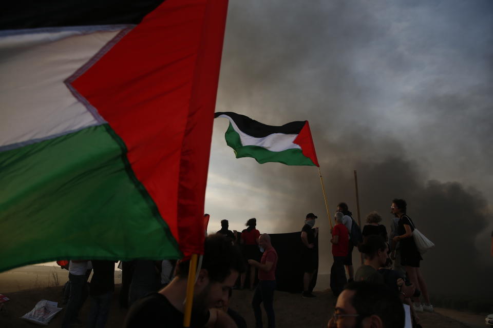 Israeli peace activists hold Palestinian flags during a protest on Israel Gaza border, Friday, Oct. 5, 2018. (AP Photo/Ariel Schalit)