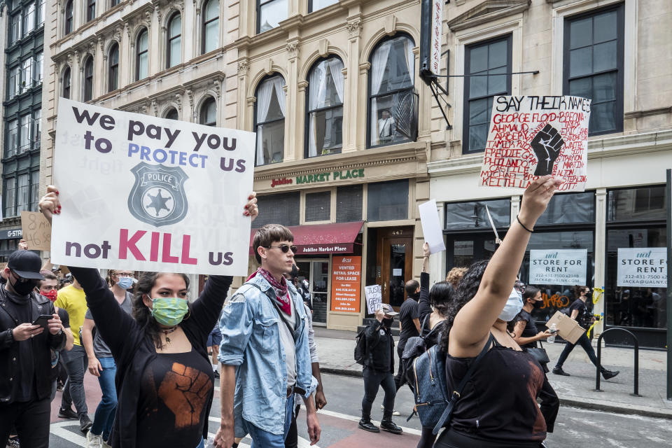 <i>New York City demonstrators walk from Foley Square past 1 Police Plaza on their way to Washington Square Park for a peaceful moment of reflection for those killed by police. The sign on the left reads: "We pay you to protect us, not kill us."</i>