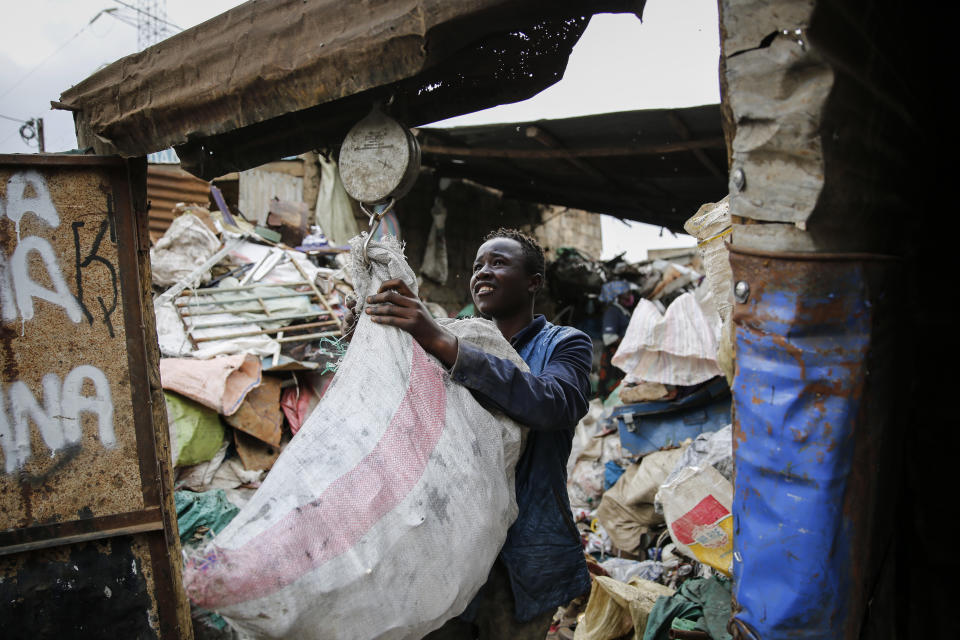 FILE - In this Saturday, Sept. 26, 2020 file photo, Peter Kihika, 16, who wants to become a teacher, weighs scavenged materials to be sold for recycling, at Kenya's largest landfill Dandora where Peter now works after his mother lost her job and his school was closed due to the coronavirus pandemic, in Nairobi, Kenya. As schools reopen in some African countries after months of lockdown, relief is matched by anxiety over everything from how to raise tuition fees amid the financial strain wrought by the COVID-19 pandemic to how to protect students in crowded classrooms. (AP Photo/Brian Inganga, File)