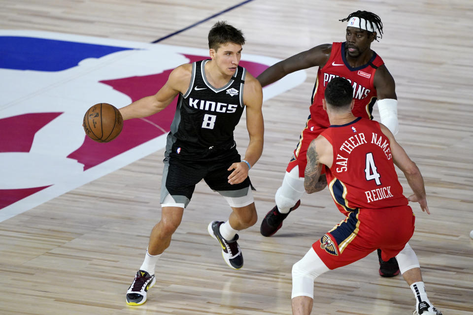 Sacramento Kings' Bogdan Bogdanovic (8) drives against New Orleans Pelicans' Jrue Holiday, back right, and JJ Redick (4) during the second half of an NBA basketball game Thursday, Aug. 6, 2020 in Lake Buena Vista, Fla. (AP Photo/Ashley Landis, Pool)