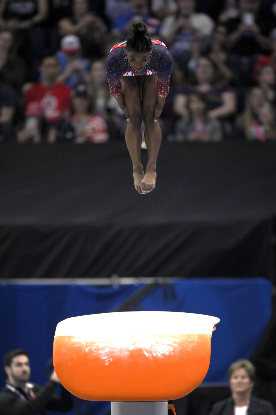 Simone Biles mid-air performing a vault routine during a gymnastics competition