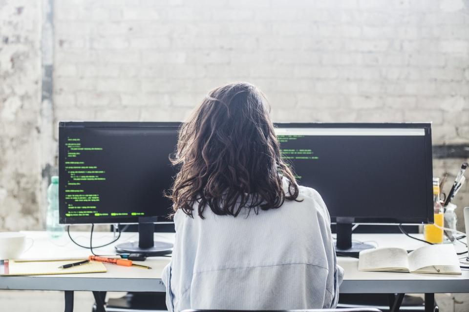 Una joven frente a dos computadoras