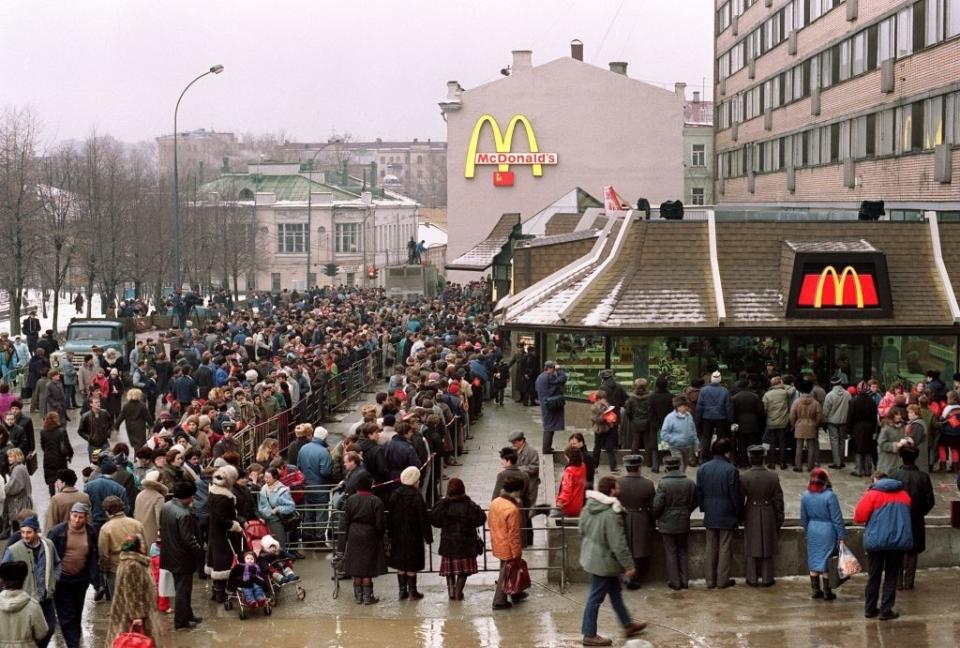 A very long, winding line extending into a bigger crowd surrounds a McDonald's