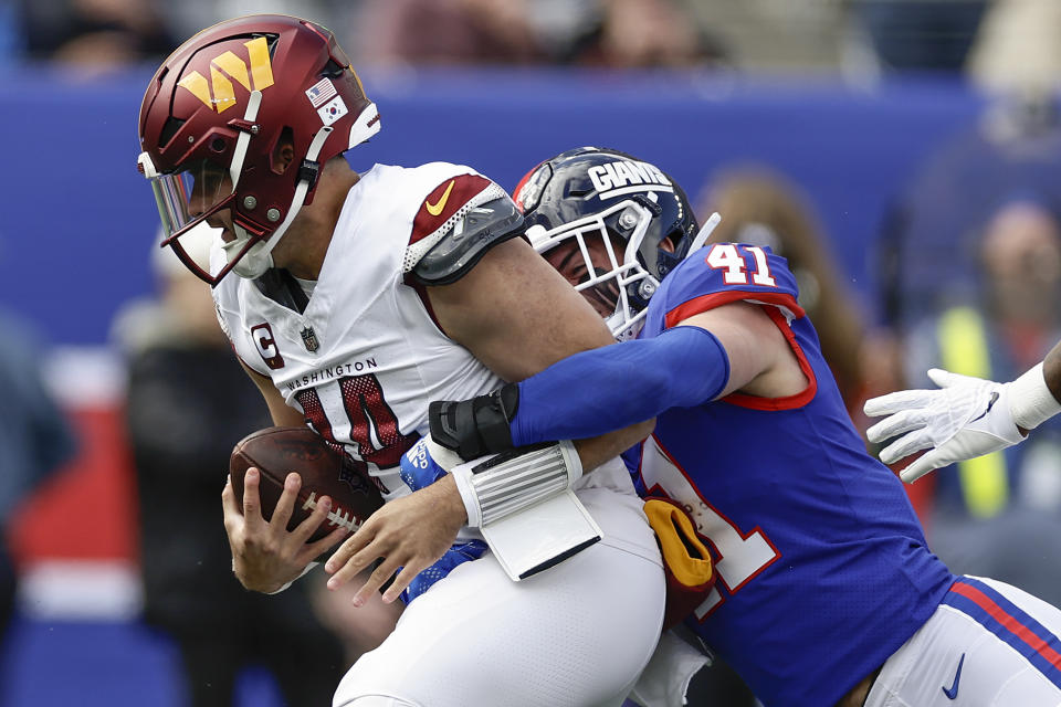 Washington Commanders quarterback Sam Howell (14) is sacked by New York Giants linebacker Micah McFadden (41) during the first quarter an NFL football game, Sunday, Oct. 22, 2023, in East Rutherford, N.J. (AP Photo/Adam Hunger)