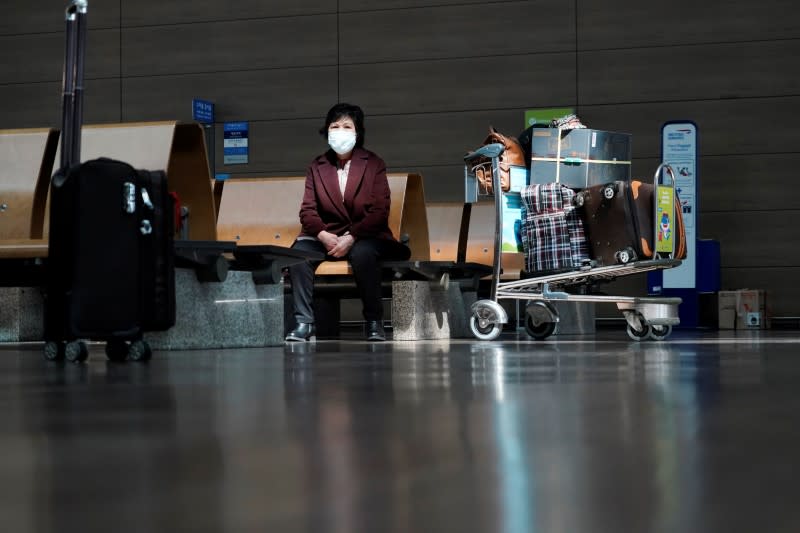A woman wearing a mask to prevent contracting the coronavirus waits for her flight at Incheon International Airport in Incheon