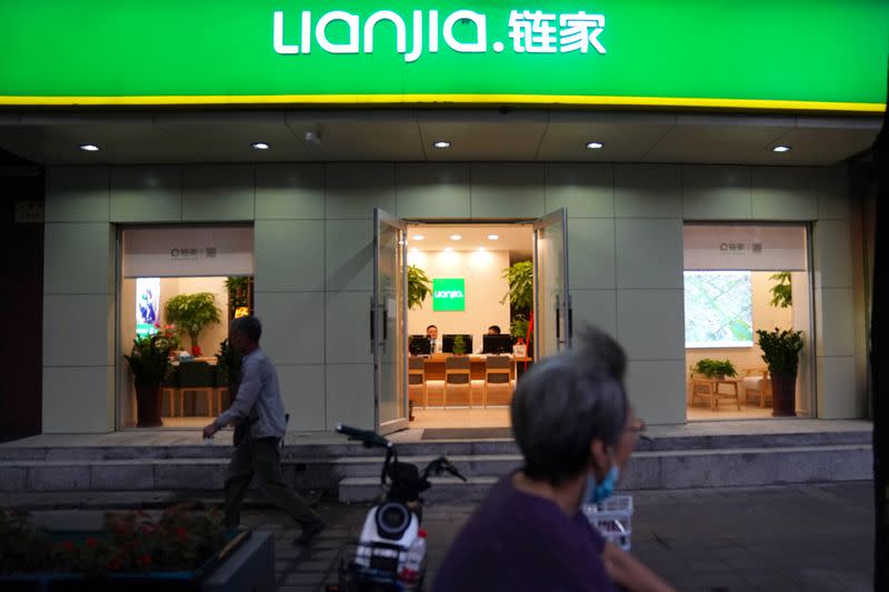 Woman wearing a face mask following the coronavirus disease (COVID-19) outbreak rides past past real estate broker Lianjia near a residential compound in Beijing