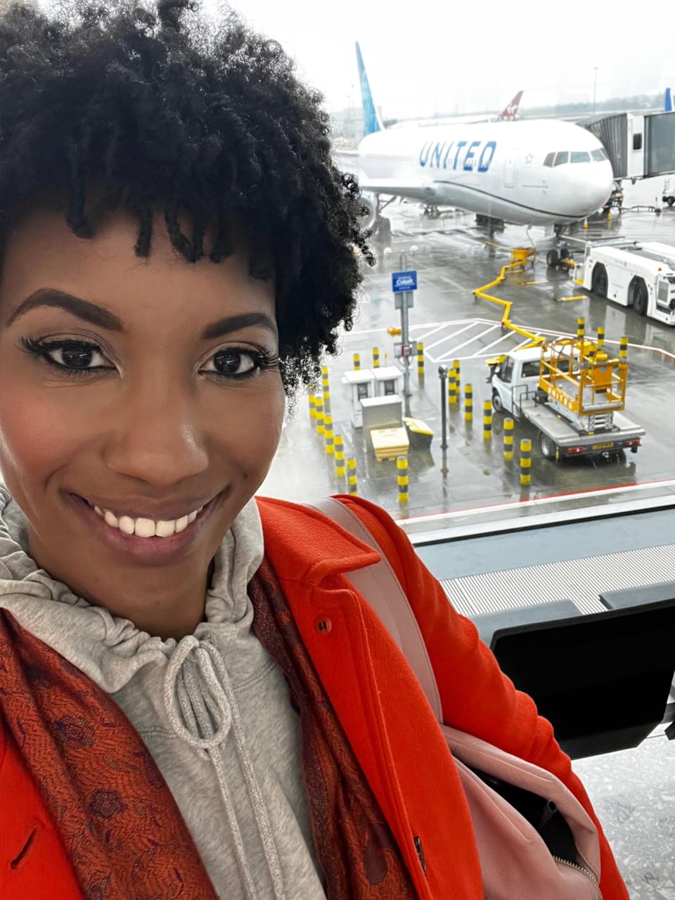 Author posing next to a United Airlines plane, which is on the tarmac.