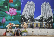 FILE - In this April 29, 2015, file photo, a snack and fruit vendor waits for customers near the advertisement board of a shopping mall and apartment building in Ho Chi Minh City, Vietnam. Vietnam, the location of U.S. President Donald Trump’s next meeting with North Korean leader Kim Jong Un, has come a long way since the U.S. abandoned its war against communist North Vietnam in the 1970s. (AP Photo/Dita Alangkara, File)