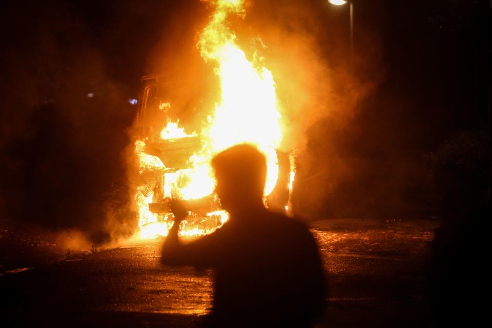 A protestor walks past a burning police vehicle after thousands of people, angry at the return of a weekend coronavirus curfew, gathered in protest in front of the National Assembly building in Belgrade, on July 7, 2020. - The crowds protested in the city centre over the government's handling of the crisis, with infections now spiking after Serbia shed its initial lockdown measures two months ago.
Scuffles broke out between police and a group of protesters who stormed into the parliament building and police unleashed tear gas canisters to disperse the crowd.
The demonstrators, who also lit flares and were seen throwing stones at police on local TV, chanted for President Aleksandar Vucic to "Resign!". (Photo by Oliver BUNIC / AFP) (Photo by OLIVER BUNIC/AFP via Getty Images)