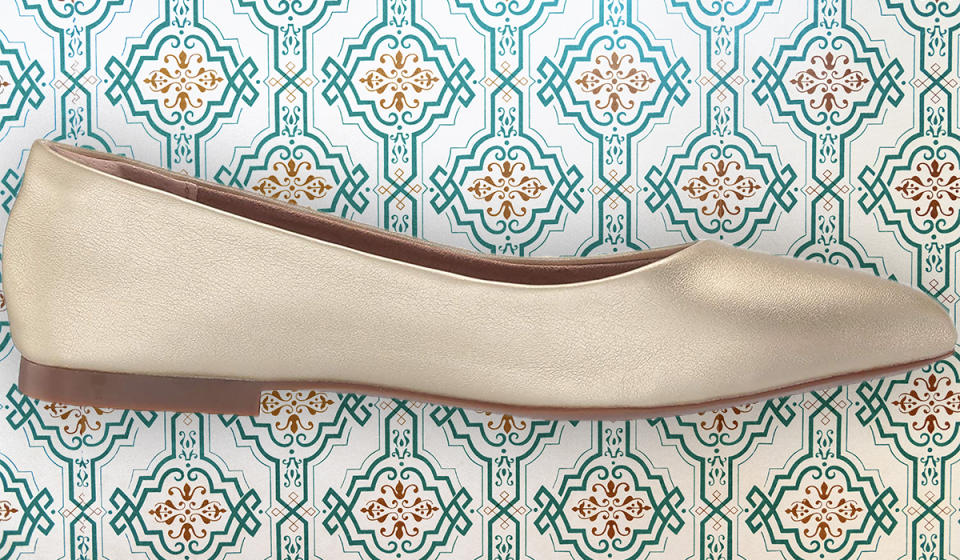 Singular gold pointed toe ballet flat shown from the side. 