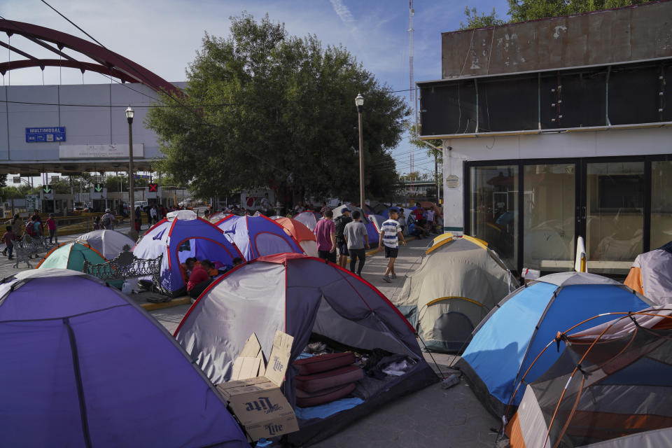 In this Aug. 30, 2019, photo, asylum seekers walk by an encampment near the Gateway International Bridge in Matamoros, Mexico. Many shelters in Mexico border are at or above capacity already, and some families have been sleeping in tents or on blankets in the blistering summer heat. (AP Photo/Veronica G. Cardenas)