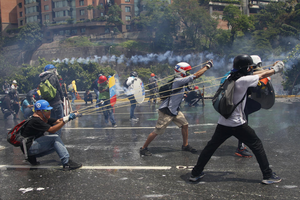 ARCHIVO - Manifestantes contra el gobierno se coordinan para lanzar una botella con material fecal a las fuerzas de seguridad que impiden el paso de la marcha rumbo a la Corte Suprema, en Caracas, Venezuela, el 10 de mayo de 2017. (AP Foto/Ariana Cubillos, Archivo)