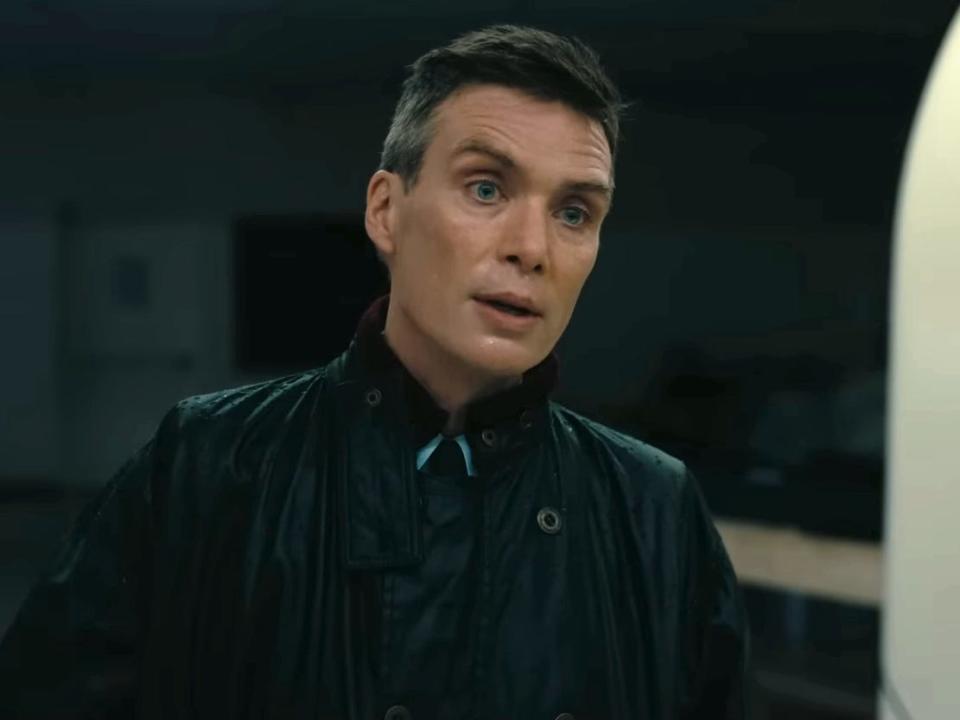 Cillian Murphy as J. Robert Oppenheimer, wearing a black raincoat.