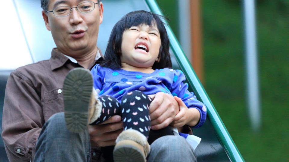 Dad on slide with child wincing