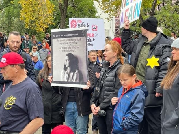 Protesters in Calgary held signs comparing the plight of Jewish victims of the Holocaust to workers who are being asked by their employers to get vaccinated for COVID-19 (and who can access medical or religious exemptions).  (Anis Heydari/CBC - image credit)