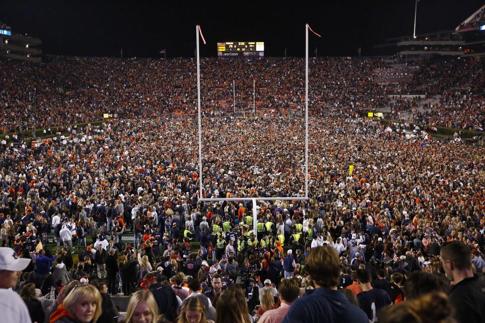 FILE - Fans rush the field after Auburn defeated Alabama in the Iron Bowl NCAA college football game, Saturday, Nov. 25, 2017, in Auburn, Ala. What is most commonly referred to as major college football (aka NCAA Division I Bowl Subdivision or FBS) is compromised of 130 teams and 10 conferences. Seventy-seven of those teams are scheduled to play throughout the fall, starting at various times in September. The other 53, including the entire Big Ten and Pac-12, have postponed their seasons and are hoping to make them up later. That means no No. 2 Ohio State, No. 7 Penn State, No. 9 Oregon and six other teams that were ranked in the preseason AP Top 25. (AP Photo/Brynn Anderson, File)