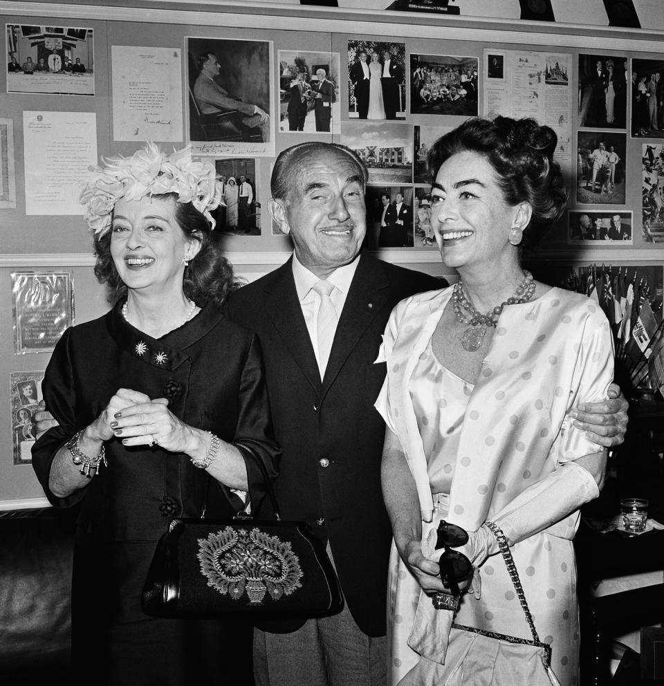 Bette Davis (izquierda) y Joan Crawford flanquean al millonario Jack Warner de los estudios Warner Brother's en 1962. (AP)