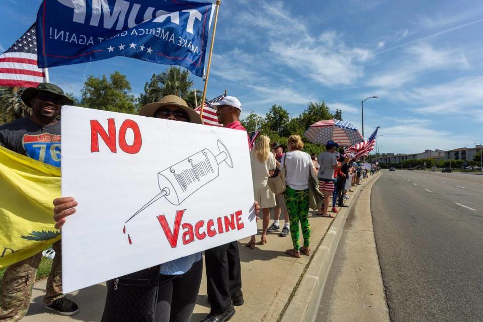 A protester holds an anti-vaccination sign at a pro-Trump rally in May.