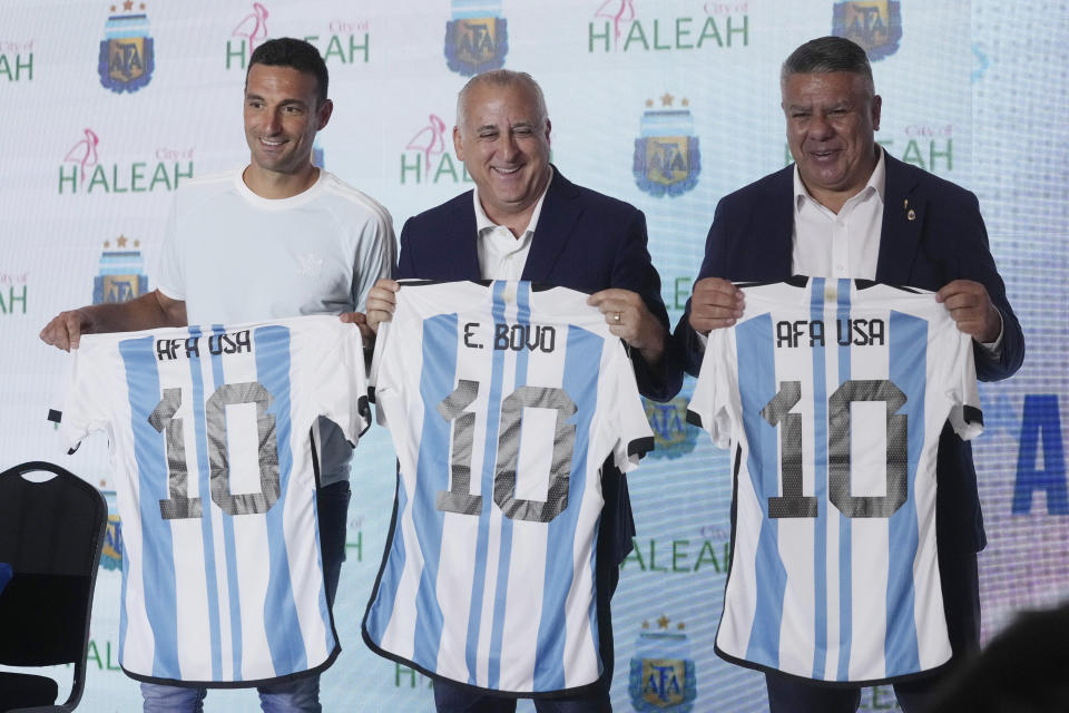 Lionel Scaloni, el director técnico de la selección argentina de fútbol, a la izquieda; Esteban Bovo, alcalde de Hialeah, Florida; y Claudio Tapia, presidente de la Asociación del Fútbol Argentino, a la derecha, sostienen las camisetas del seleccionado nacional argentino tras una rueda de prensa el martes 15 de agosto de 2023 en Hialeah, Florida. La AFA anunció sus planes de construir un predio de alto rendimiento en el área de Miami y de crear una academia para divisiones inferiores en Estados Unidos. (AP Foto/Marta Lavandier)