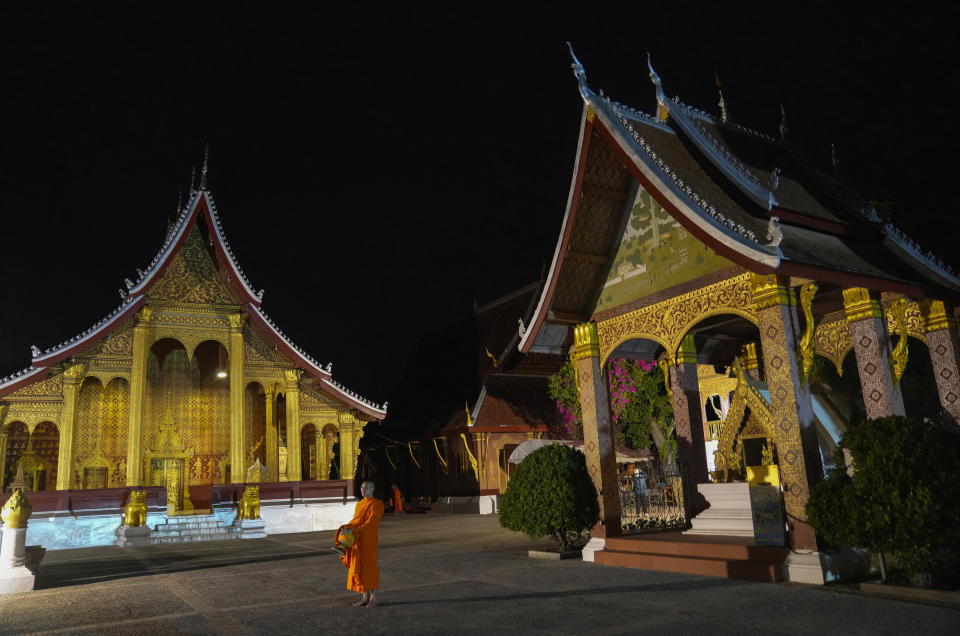 Buddhist monks walk inside Sensoukharam temple aim for food in Luang Prabang, Laos, Sunday, Jan. 28, 2024. Luang Prabang was named a UNESCO World Heritage Site nearly 30 years ago, but a multibillion-dollar dam project is raising questions that could deprive the city of its coveted status and prompting broader concerns the Mekong River could be ruined by multiple dams that are being planned.(AP Photo/Sakchai Lalit)