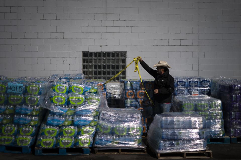 Volunteer David Graham organizes pallets of bottles at a water distribution sight at Brittain Chevrolet in East Palestine, Ohio, Tuesday, March 7, 2023. The railroad says testing shows drinking water is safe, though it's establishing a fund for long-term drinking water protection. (AP Photo/Matt Rourke)