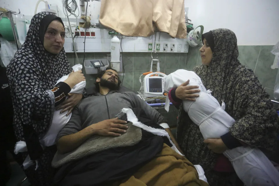 A Palestinian woman shows the body of her grandchild, her father after it was killed in the Israeli bombardment of the Gaza Strip outside a morgue in Rafah, Tuesday, Dec. 19, 2023. (AP Photo/Hatem Ali)